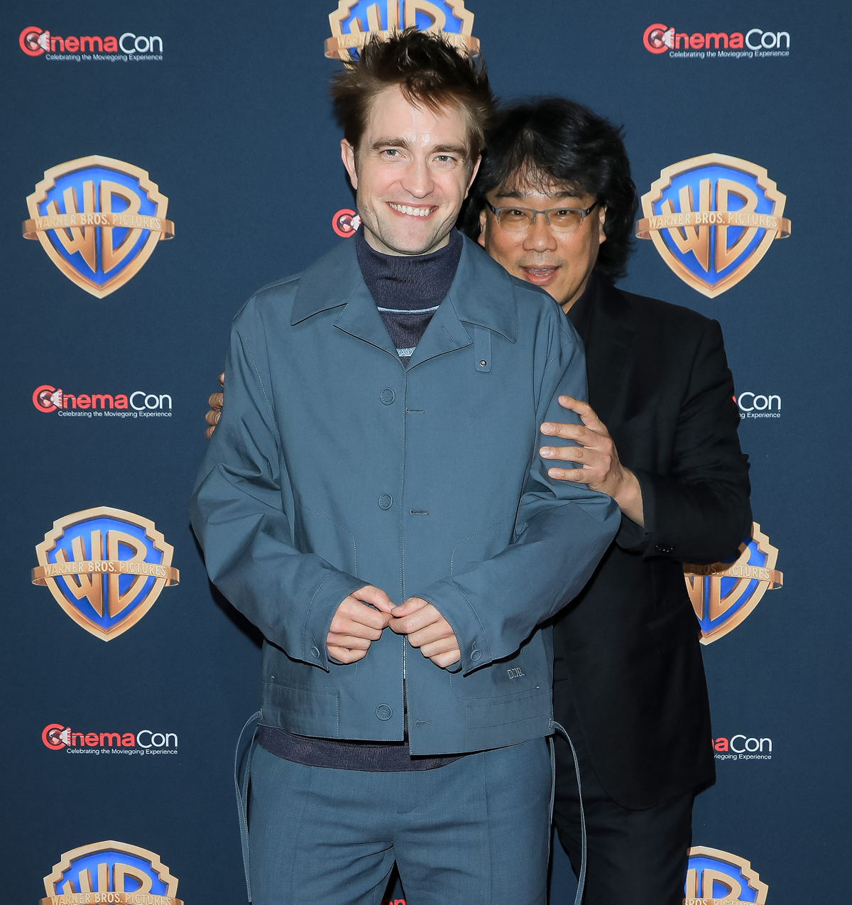 Robert Pattinson smiling at CinemaCon with director Bong Joon Ho